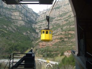 yellow cable car with whie mountains and green flora in background