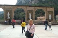 woman standing in front of white statue and mountain in montserrat spain